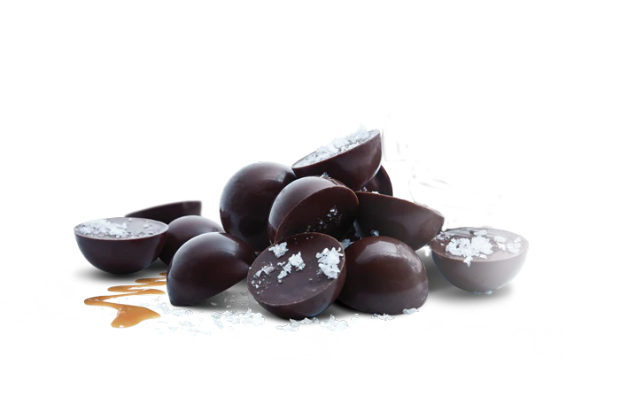 Dark chocolate half spheres with flakey salt crystals sprinkled over the top.