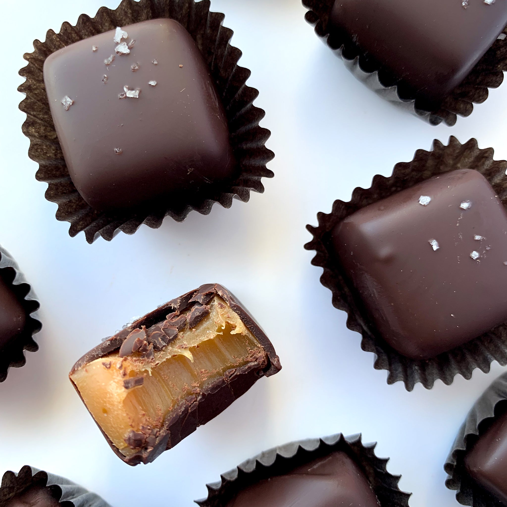 Chocolate-covered treats with one cut open to reveal a filling on a white background