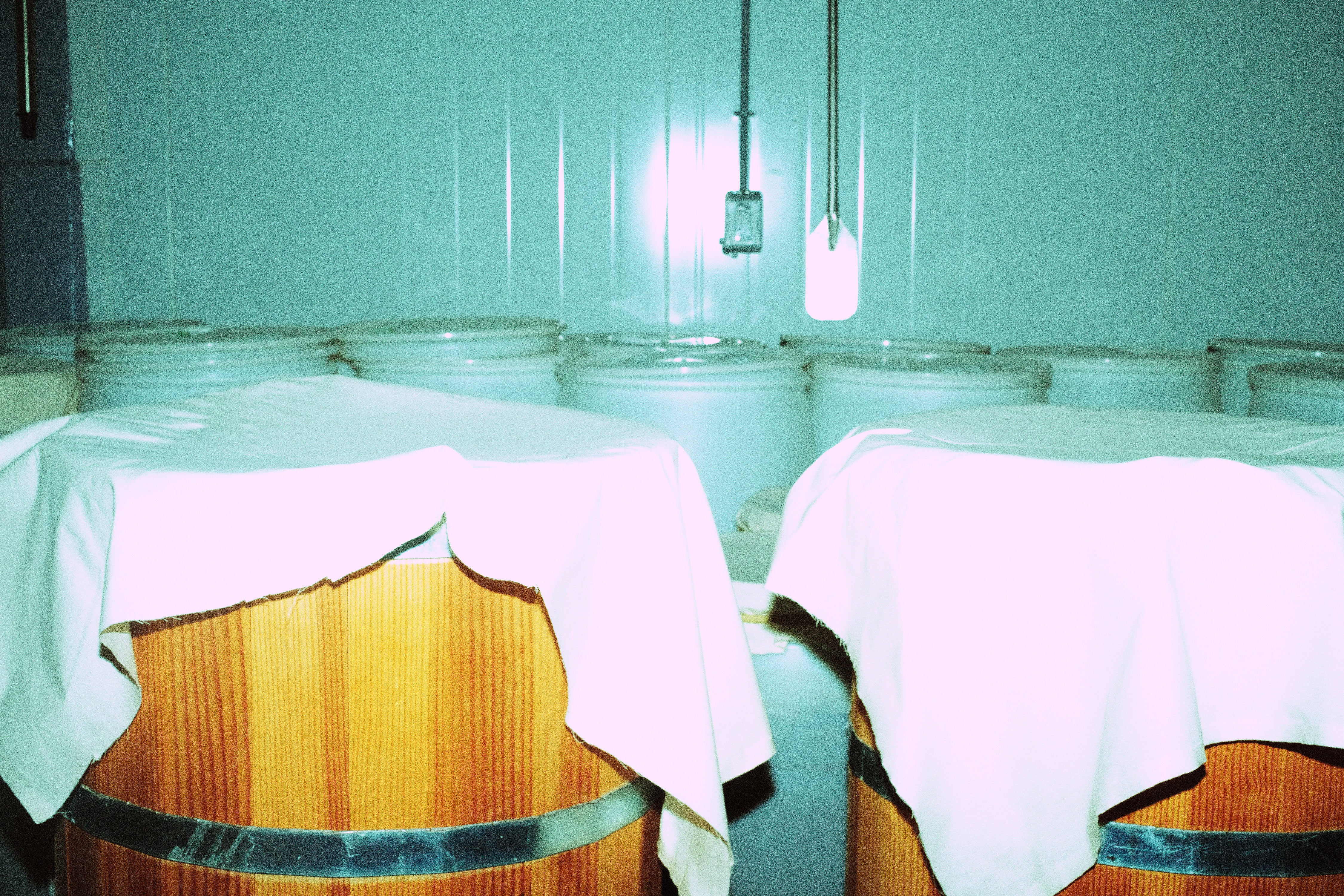 Two wooden barrels with white cloths draped over them against a teal wall.