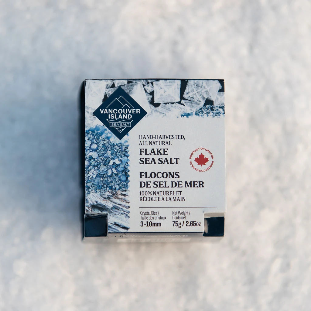 Flake Sea Salt 75 g sleeve resting on a bed of our own flake sea salt, top view